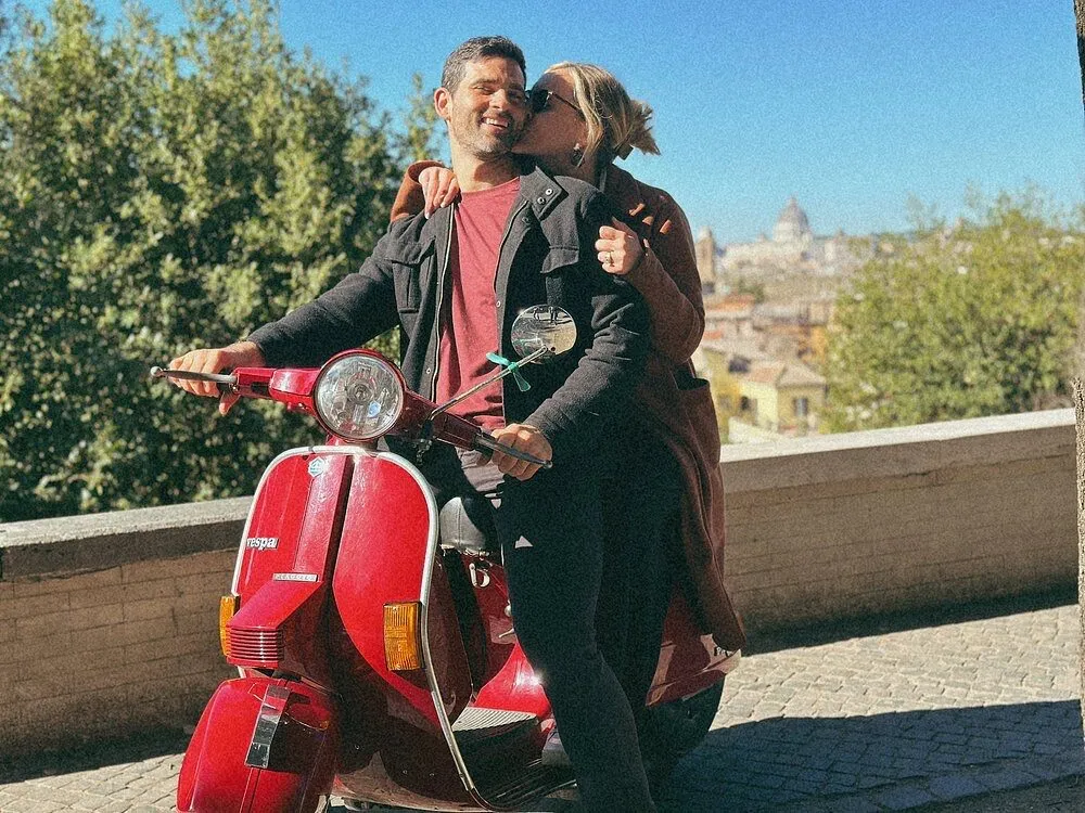 Couple embracing on a Vespa with a panoramic view over Rome