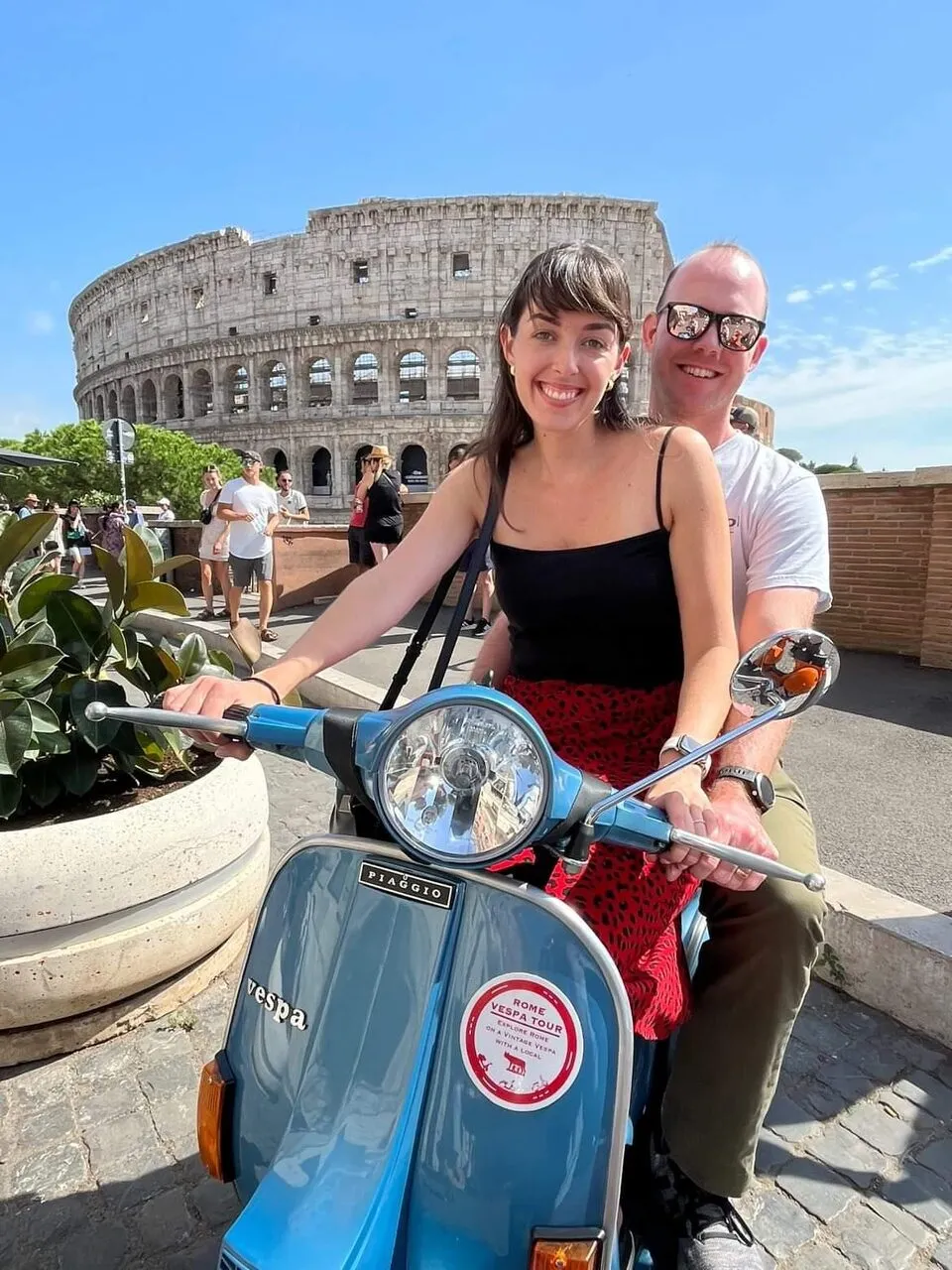 Couple on a Vespa with the Colosseum behind them
