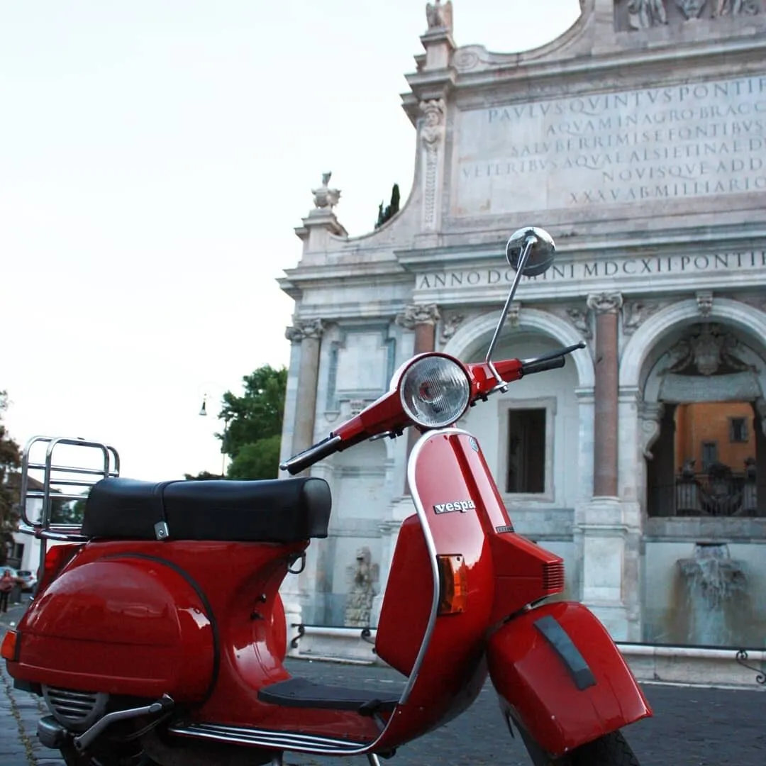 Red Vespa parked in front of the Acqua Paola fountain on the Janiculum Hill