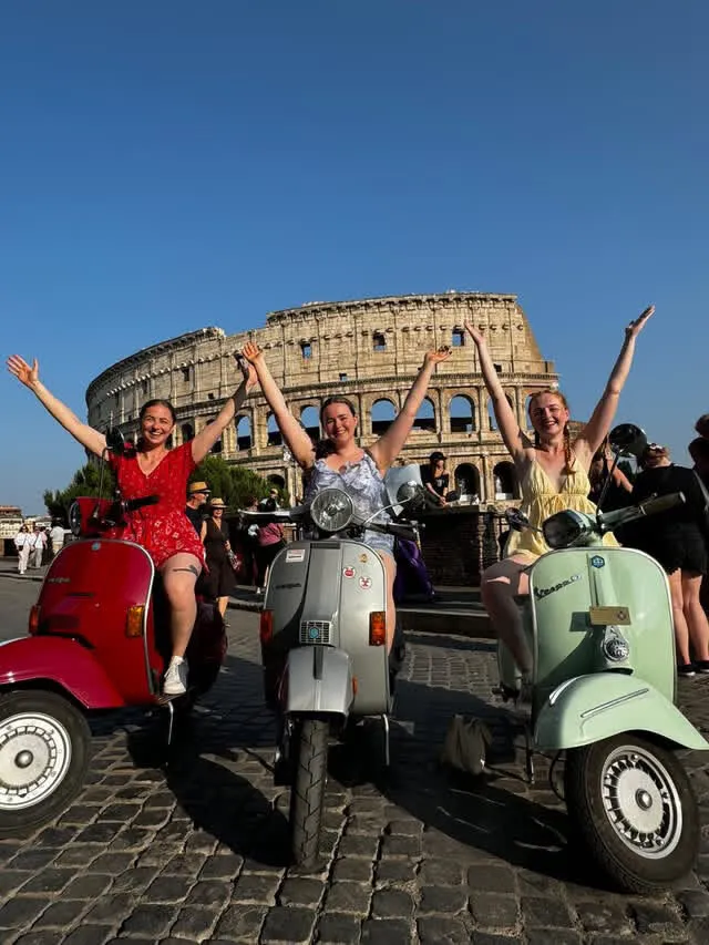 Cheerful group on Vespas in front of the Colosseum