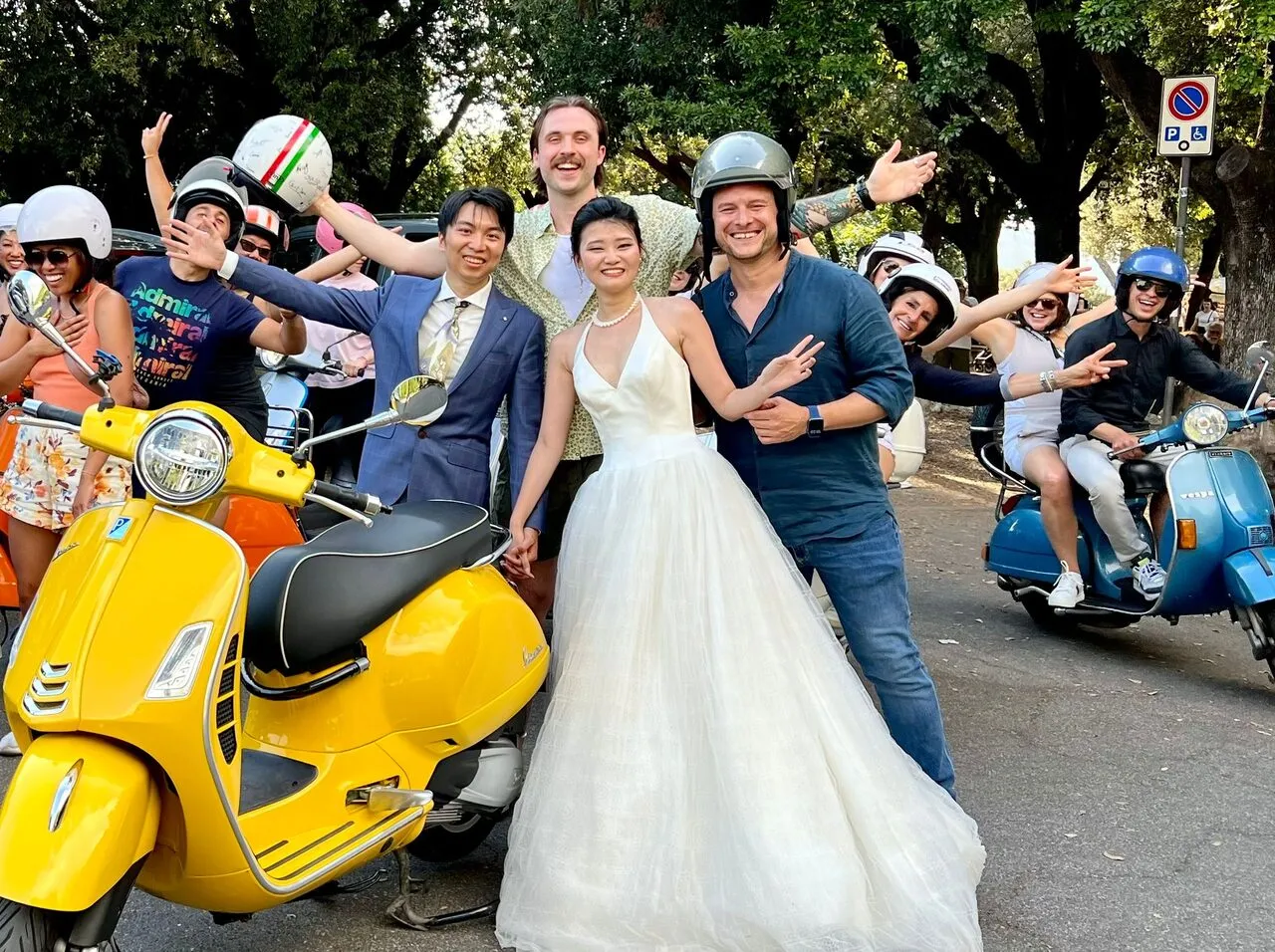 Bride and groom posing with a yellow Vespa alongside the tour group